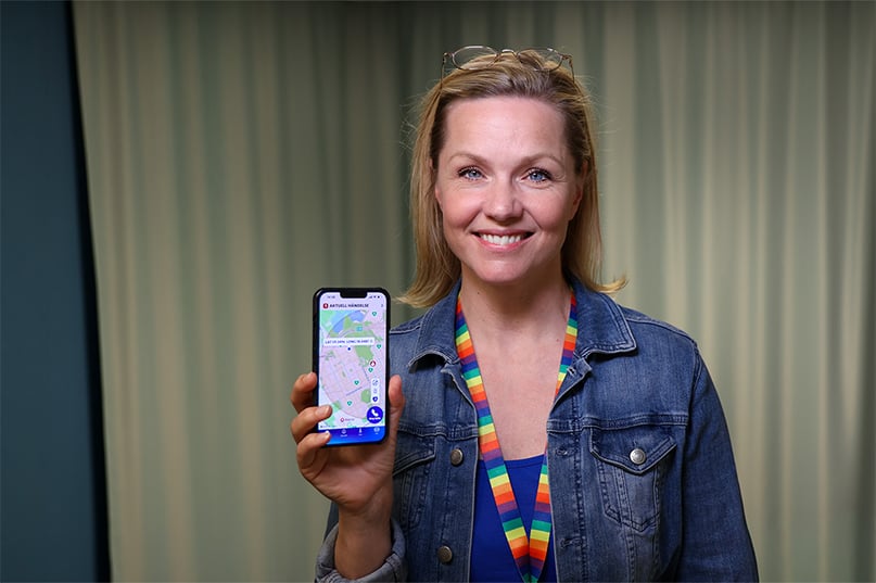 SOS Alarm medarbetare som håller upp en mobil som visar 112-appen. 