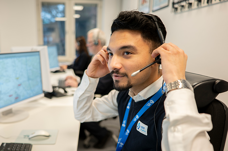 Person med headset justerar mikrofonen vid en arbetsstation i en larmcentral.