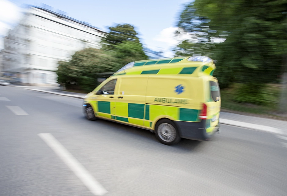 Ambulans som åker på tätbebyggd väg.