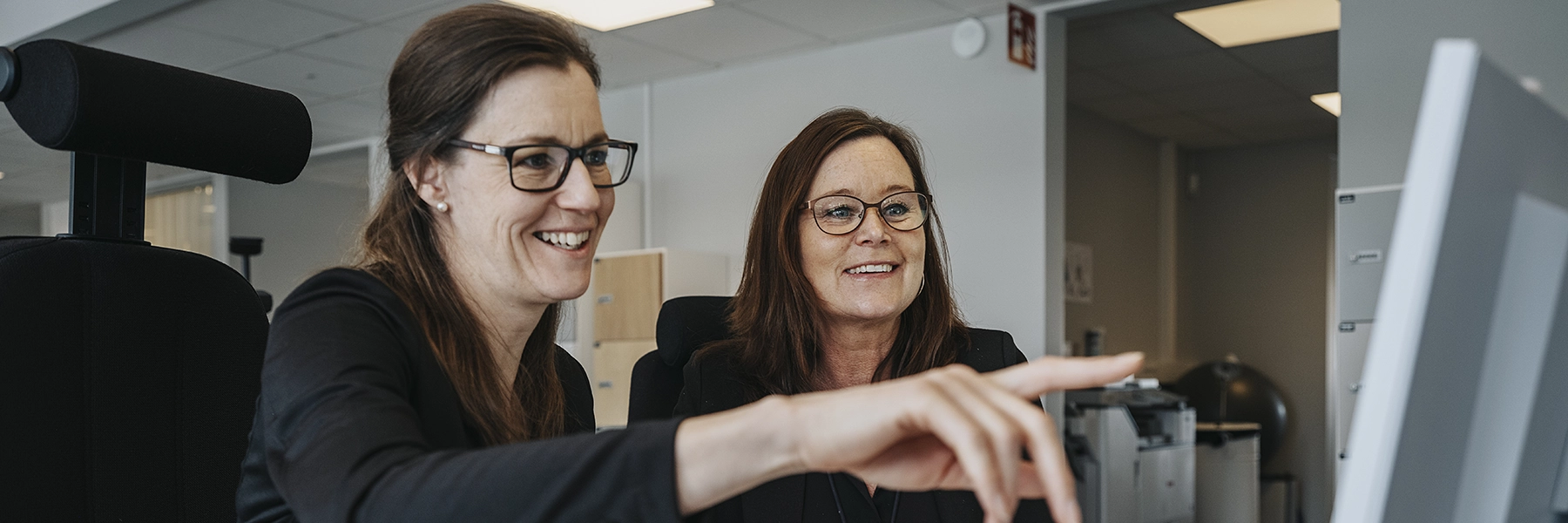 Två kvinnor som sitter framför en dator.