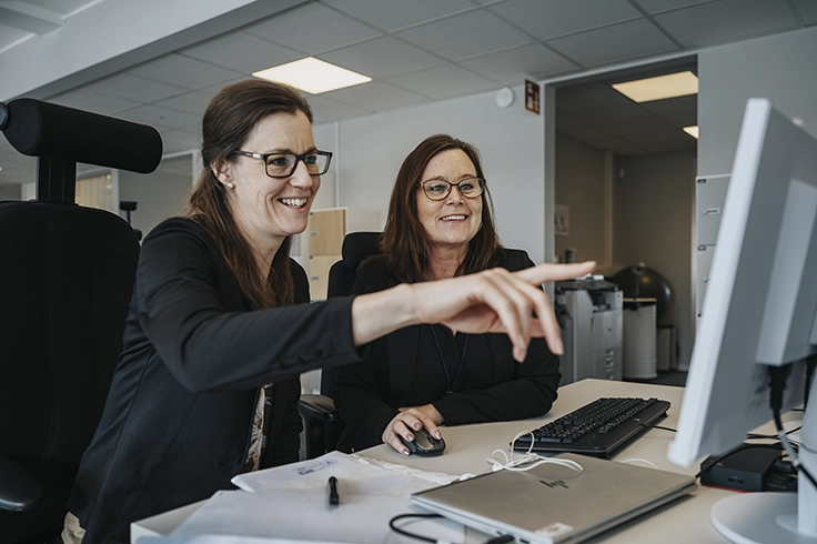 Två avtalsansvariga på SOS Alarm i en dialog framför en dator.