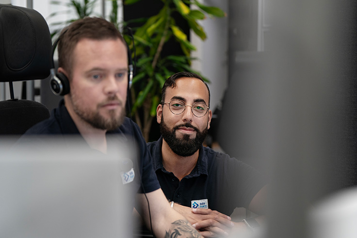 Två medarbetare på SOS Alarm som sitter framför en arbetsstation och svarar på 112.